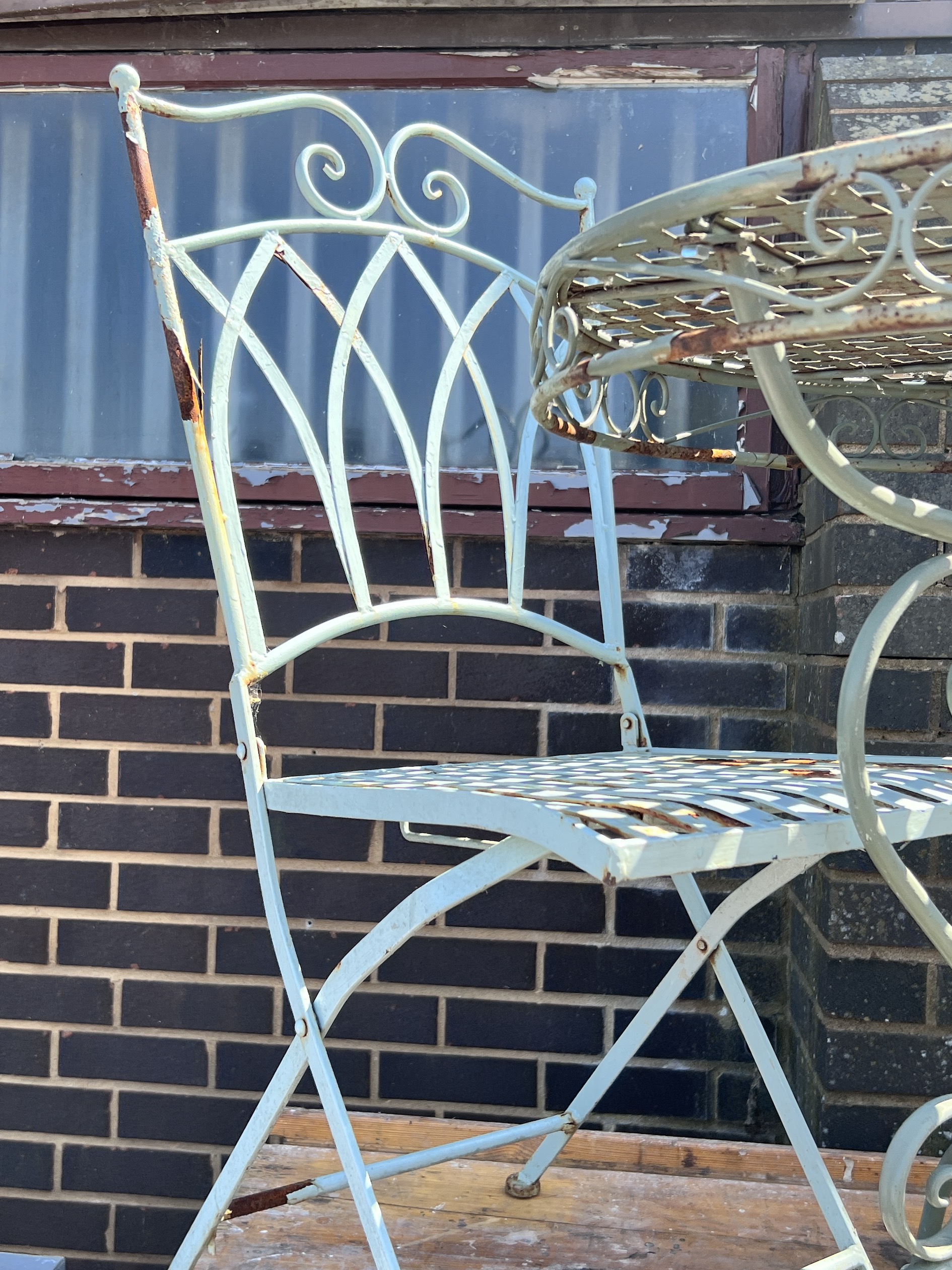 A circular painted metal garden table, diameter 70cm, height 74cm, and two chairs